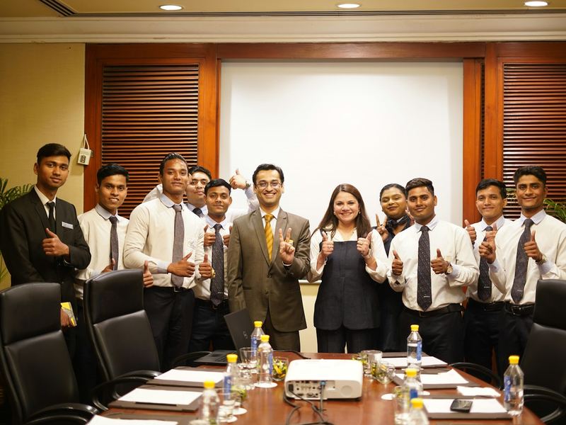 A group of young professionals holding certificates at a ceremony in a conference room