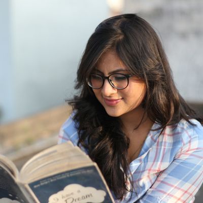 Portrait of a young woman with glasses reading a book