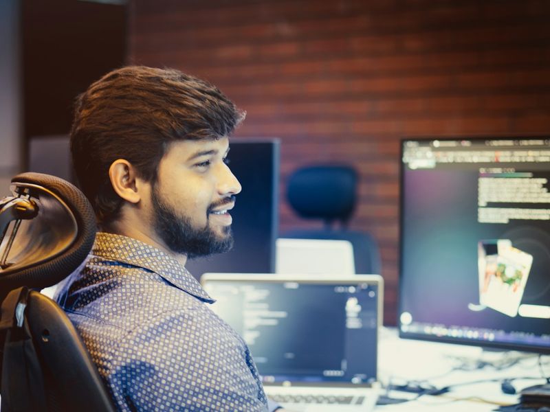A smiling young developer at his workstation in an IT office